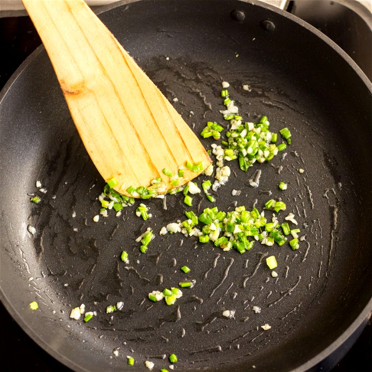 Image of Fry the spring onion and garlicIn a small wok or...
